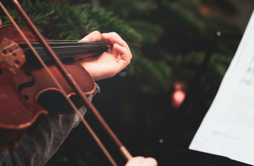 ein Mädchen spielt am Weihnachtsbaum auf einer Violine neben dem Notenständer mit Notenblatt