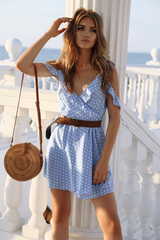 beautiful sensual woman with blond hair in elegant dress and accessories posing on the summer beach