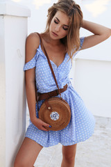 beautiful sensual woman with blond hair in elegant dress and accessories posing on the summer beach