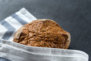 loaf of rye bread on towel on black background