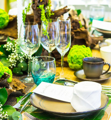 Party dinner table setting with tableware and silverware and glasses set and Candlestick and flower in restaurant.