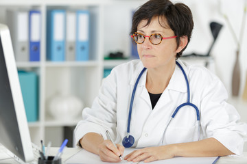 middle aged female doctor sitting in front of laptop