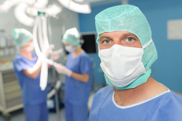 handsome surgeon in mask is looking at camera