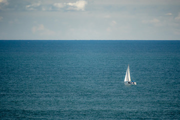 Isolated Sailboat under full sail on blue ocean