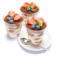 Classic tiramisu dessert with blueberries and strawberries in a glass isolated on a white background with clipping path
