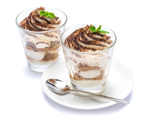 Classic tiramisu dessert in a glass on plate with spoon isolated on a white with clipping path