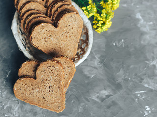 Rye bread in the shape of heart cut into slices on a gray background