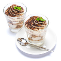 Classic tiramisu dessert in a glass on plate with spoon isolated on a white with clipping path