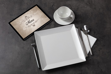 Tablet with stylish restaurant logo and laid table
