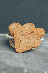 Rye bread in the shape of heart cut into slices on a gray background