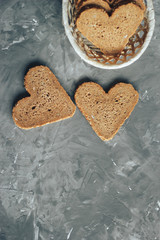 Rye bread in the shape of heart cut into slices on a gray background