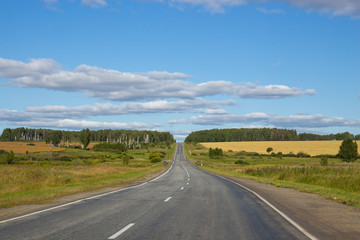 the road meanders away into the distance, on top of a cloudy sky