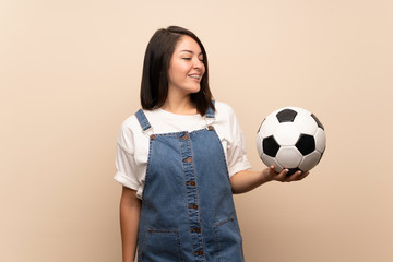 Young Mexican woman over isolated background holding a soccer ball