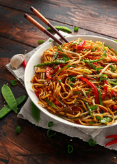 Chow mein, noodles and vegetables dish with wooden chopsticks
