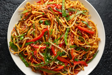 Chow mein, noodles and vegetables dish with wooden chopsticks