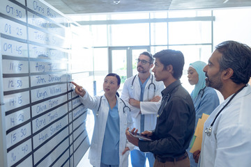 Medical team of doctors discussing their shifts on chart at hospital