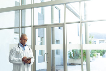 Male doctor using digital tablet in lobby at hospital