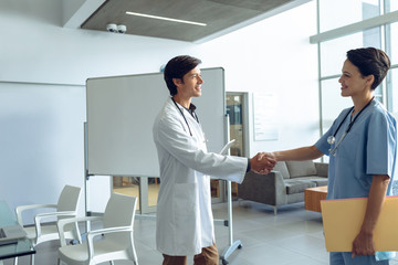 Fototapeta premium Male doctor shaking hands with female nurse in the hospital
