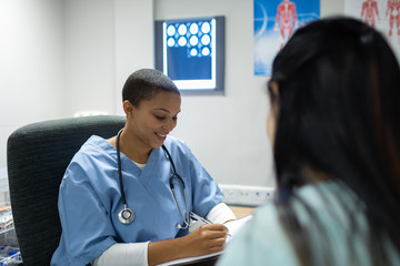 Doctor giving prescription to pregnant woman at desk