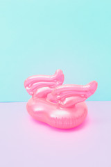 Inflatable pool toy in shape of heart with wings on pastel pink and blue background. Soft palette
