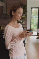 Woman holding coffee cup in kitchen 