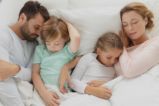 Caucasian family sleeping together in bed 