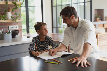 Father helping his son with homework in a comfortable home