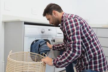 Man putting dirty clothes into the washing machine in a comfortable home