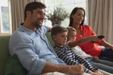 Family watching television in living room at home