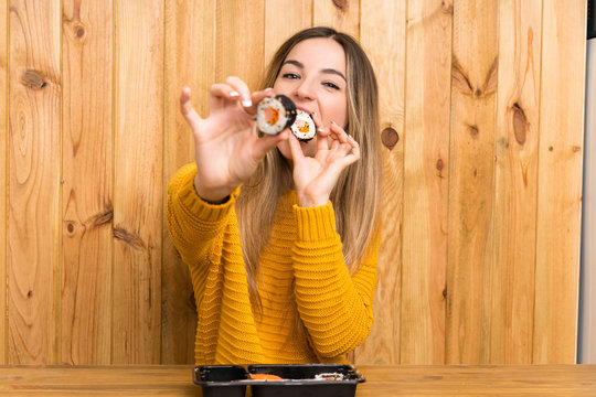 Young woman with sushi over wood background