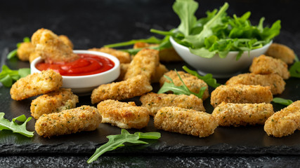 Fried mozzarella cheese sticks in breadcrumbs with ketchup sauce and wild rocket leaves