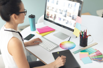 Obraz na płótnie Canvas Female graphic designer using graphic tablet at desk in a modern office