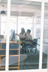 Female graphic designers discussing on computer at desk in a modern office