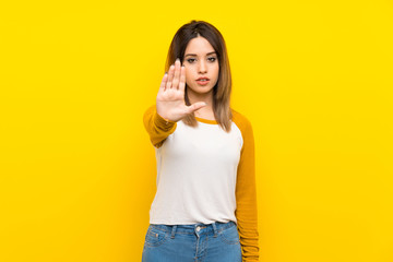 Fototapeta premium Pretty young woman over isolated yellow wall making stop gesture