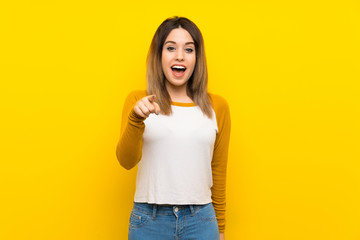 Fototapeta premium Pretty young woman over isolated yellow wall surprised and pointing front