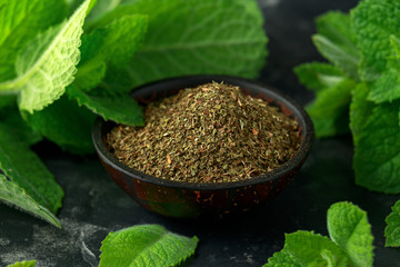Fresh and dried mint in bowl. on black rustic table