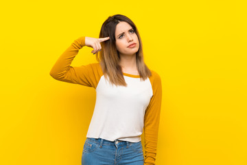 Pretty young woman over isolated yellow wall making the gesture of madness putting finger on the head