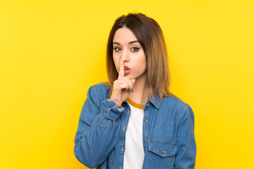 Young woman over yellow background doing silence gesture
