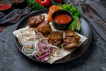 Kebab of pork on black plate