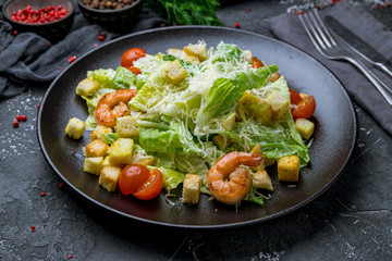 salad caesar with shrimps on black plate