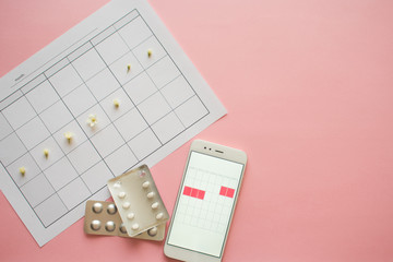 Fototapeta premium Menstrual cycle. Calendar for the month with marks and a mobile application on the smartphone screen.