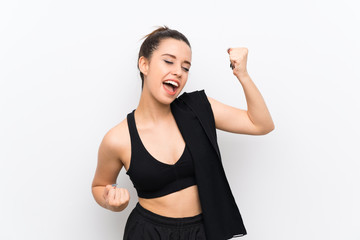 Young sport woman over white wall celebrating a victory