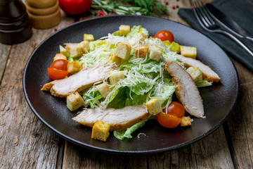 Salad caesar with chicken on black plate