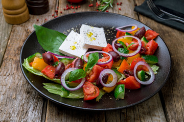 Greek salad with feta on black plate