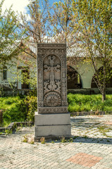 Fototapeta na wymiar Khachkar of grey stone with ethnic patterns in the courtyard of the Church of the Holy Martyrs in the village of Teghenik in Armenia