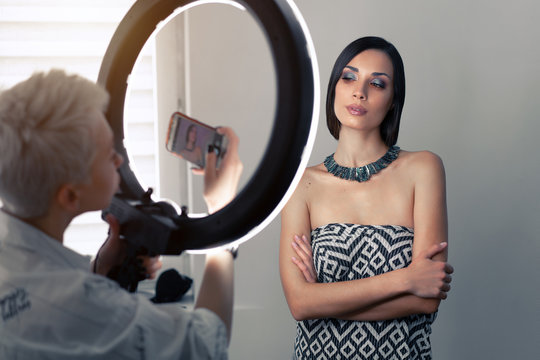 Makeup artist bsn photographs on a mobile phone the result of his work on a beautiful girl model with a ring light lamp