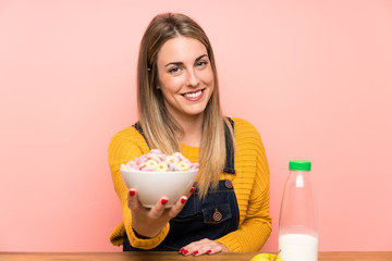 Happy Young woman with bowl of cereals over pink wall