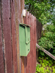 Green mailbox on a wooden fence of a country house.