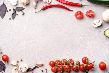 Creative layout made of seasonal summer vegetables. Healthy food concept. Cherry tomatoes, champignons, cucumber, basil leaves, garlic, chilly pepper on stone background, copy space