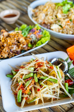 Papaya Salad with Salted Crab and Fermented Fish or Som Tam Poo Pla Ra a famous delicious food in Thailand on wood table.